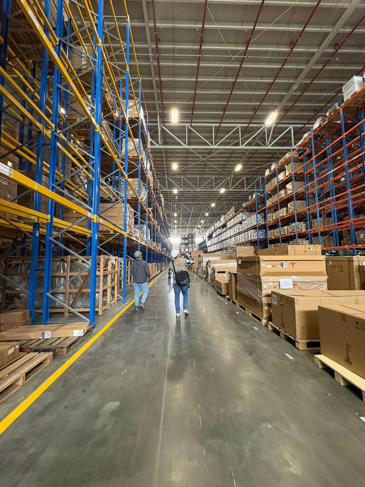Recorrido de obra en bodega industrial con racks de almacenamiento